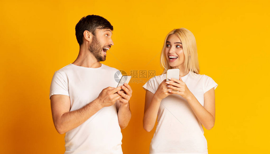 面对的交谈兴奋的男人和女人说话拿着智能手机看着对方图片