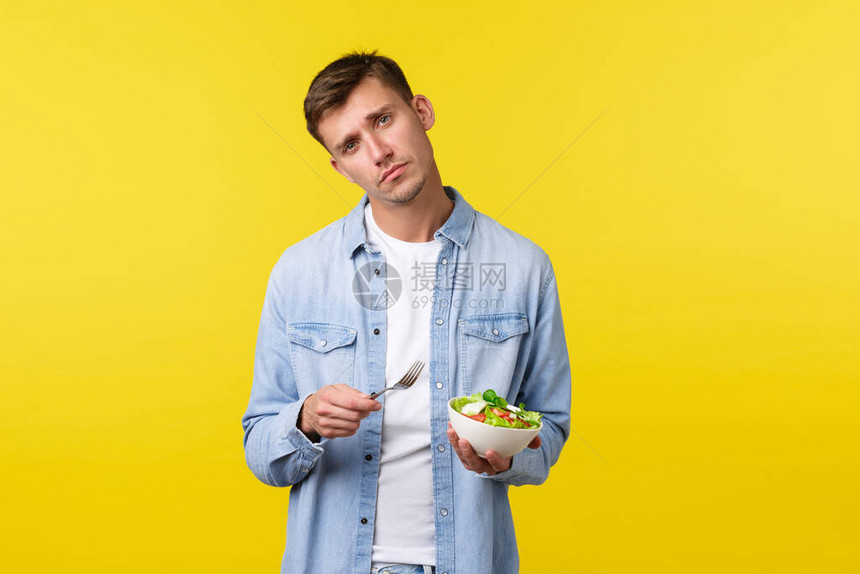 阴郁而沮丧的皱着眉头的帅哥在吃沙拉时感到悲伤图片