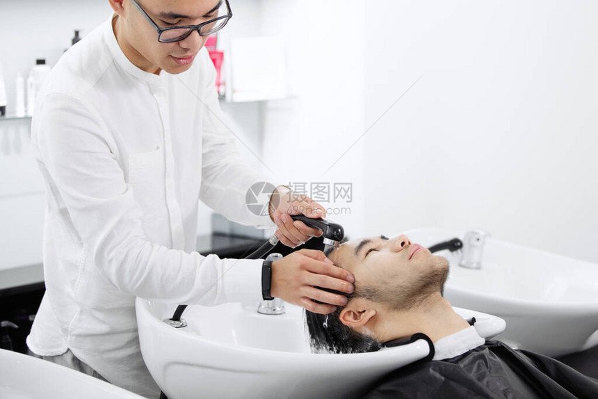 年轻理发师在剪头发前先图片