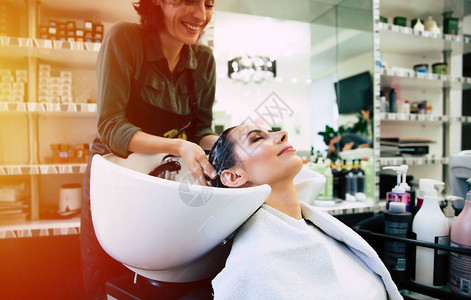 理发师洗发机头顶着她的客户在背景图片