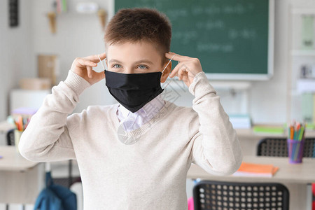 在课堂上戴着保护面具的小男孩子在课堂上被称作流图片