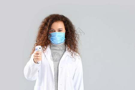 佩戴防护面具和灰色底温度计的女医生图片