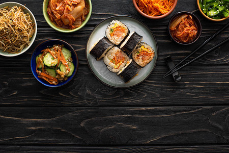 在木质表面的美味韩国菜边盘子附近图片