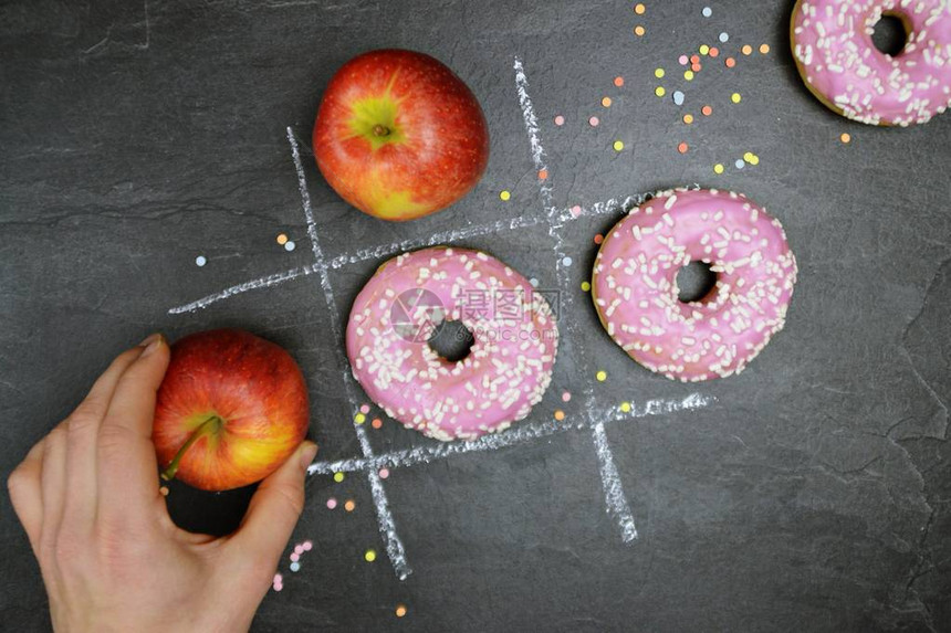手和粉笔在黑板上用糕饼和苹果绘图片