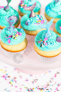 彩色美人鱼蛋糕上满是蓝色奶油糖霜装饰着洒水和巧克图片