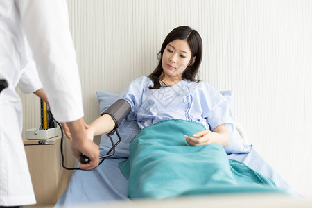 检查躺在医院床上的亚裔妇女病人血压图片