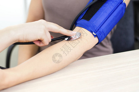 血压测量过程中听诊器钟压肱动脉的特写女医生的手按听诊器在图片