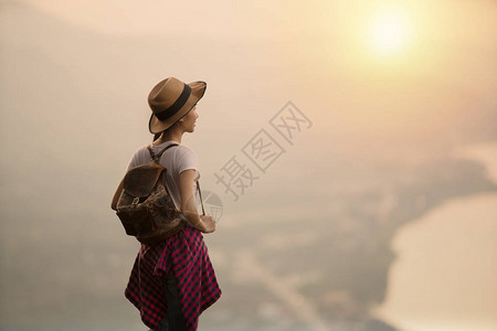 美丽的女人站在悬崖边缘日落或日图片