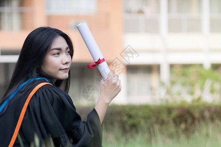 年轻的亚洲女大学毕业生穿着毕业礼服和帽子图片