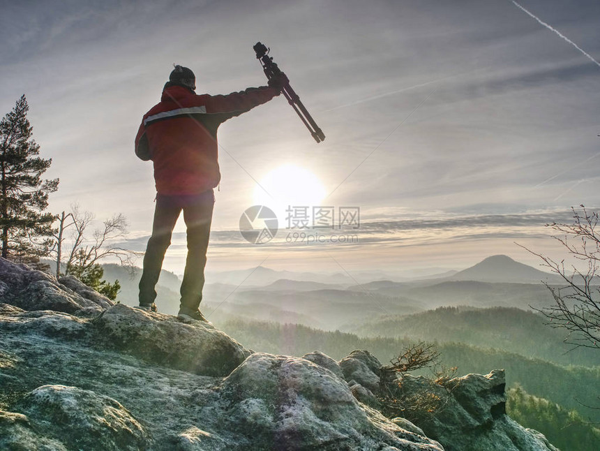 游客手持旅行三脚架摄影师登顶拍摄山顶日出图片