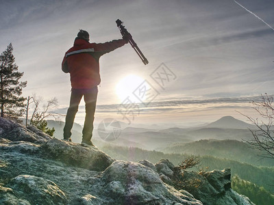 游客手持旅行三脚架摄影师登顶拍摄山顶日出图片