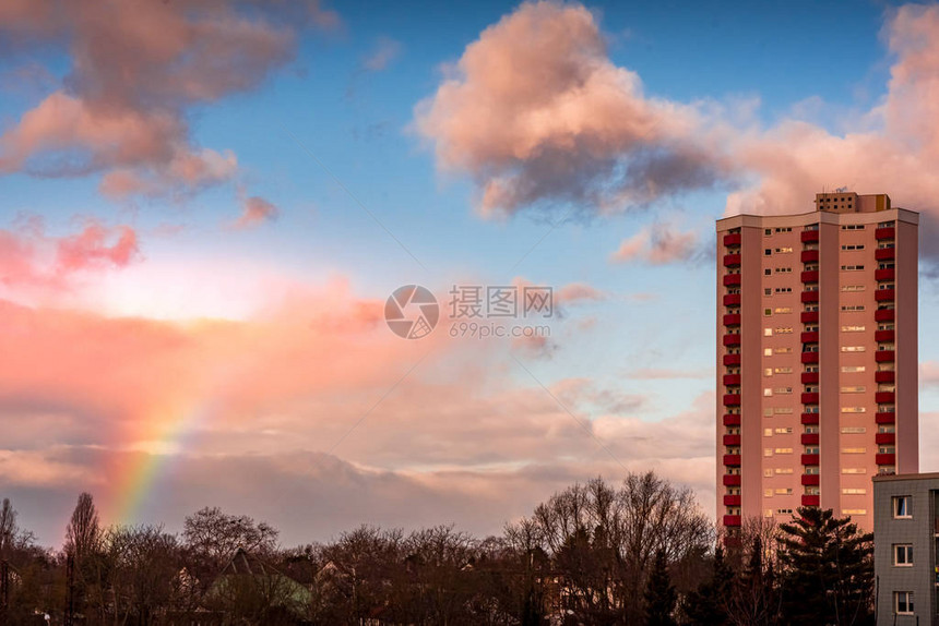 夕阳下的高楼与天空中的彩虹图片