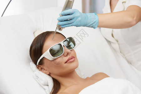 戴防护眼镜接受前额激光治疗的女图片