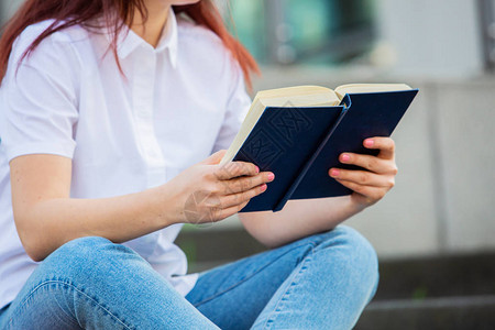 户外女大学生在校园里拿着书自信的学生拿着书在大学建筑图片