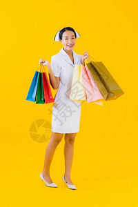 身着购物袋和信用卡黄色孤立背景的泰国女护士ThaiW图片