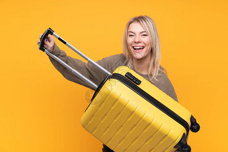 在休假时带旅行李箱的黄背景与世隔绝的金发年图片