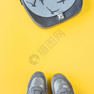 灰色和银色女运动鞋以及黄色光彩背景的袋子秋天时装概念图片
