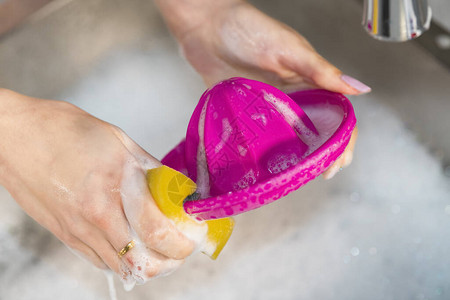 妇女用肥皂和海绵在厨房水槽上洗一个塑料压榨机图片