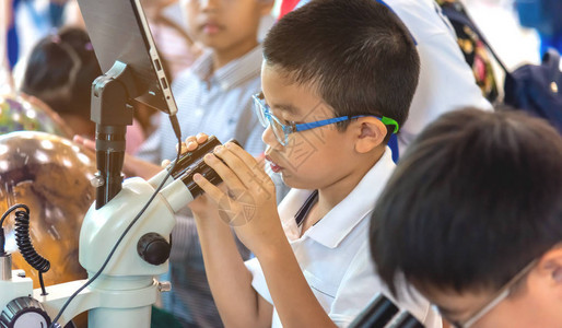 亚洲小男孩的图像使用显微镜在学校实验图片
