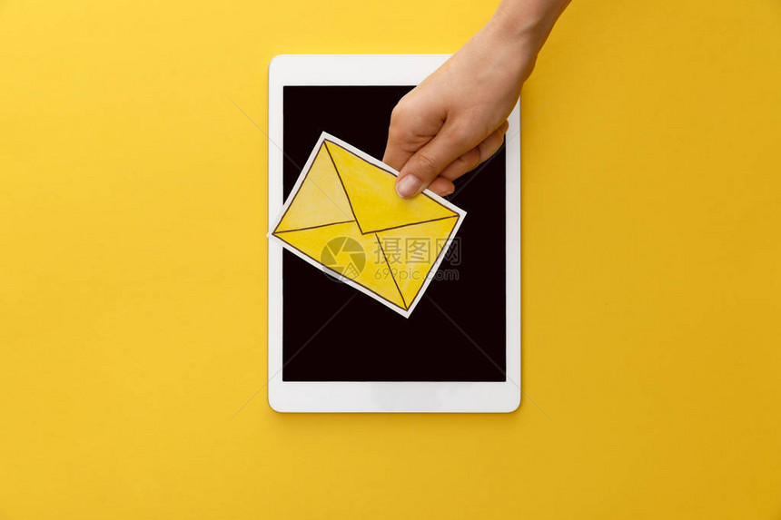 女在数字平板下用黄色背景的空白屏幕持有信件的作图片