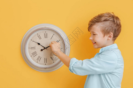小男孩在彩色墙上触摸时钟箭头图片