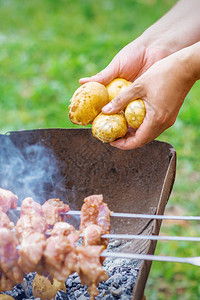 人的手在户外用火烧烤肉用烤肉串烤土豆生活方式乡村食图片