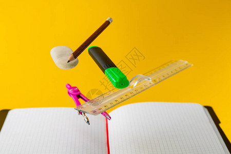 悬浮数用品笔记本钢笔尺子铅笔分隔线和黄色背景的橡皮擦教育和图片