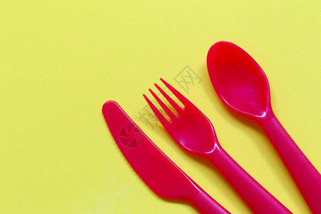 红色勺子和叉子在黄色背景上图片