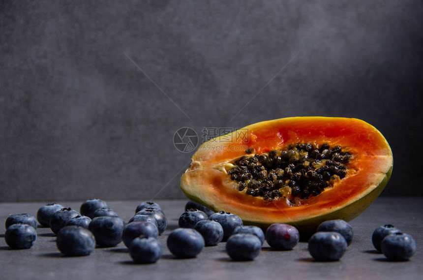 深色背景的切片木瓜和甜蓝莓水平视图片