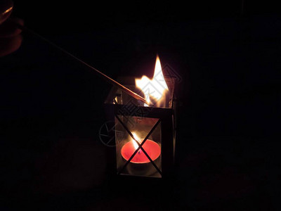 茶烛在传统小灯笼内用长火棍点燃在黑暗的夜图片