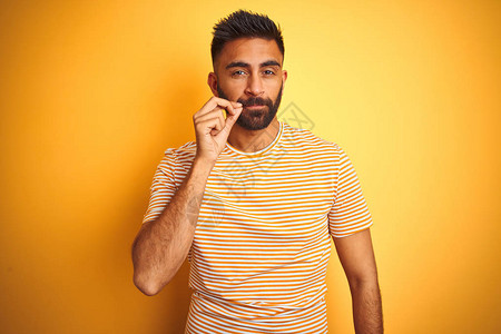 穿着T恤的印度青年男子站在孤立的黄色背景嘴唇和嘴唇上图片