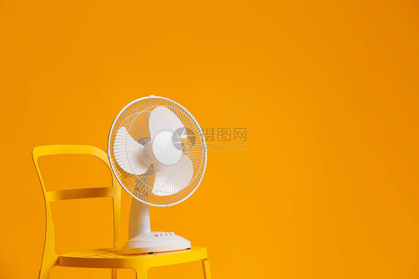 彩色背景椅子上的电风扇图片