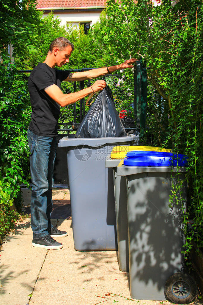 在回收箱中对生活垃圾进行选择分类的人男人把垃圾袋放在花园里图片