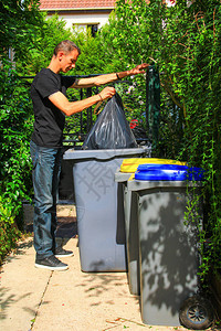 在回收箱中对生活垃圾进行选择分类的人男人把垃圾袋放在花园里图片