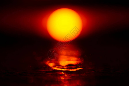日落的天空与大太阳是在水面上和bokeh光在图片