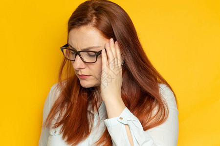 工人年轻女子在眼镜视力和黄墙背景头痛压力疲劳人的概念双手抱头图片