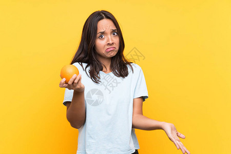 年轻棕发女人拿着橙子在抬起肩膀时做图片