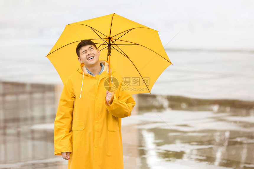 穿雨衣在城市街上带伞的图片