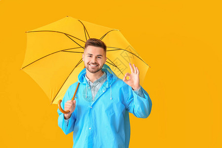 穿雨衣带雨伞的年轻人在彩色背图片