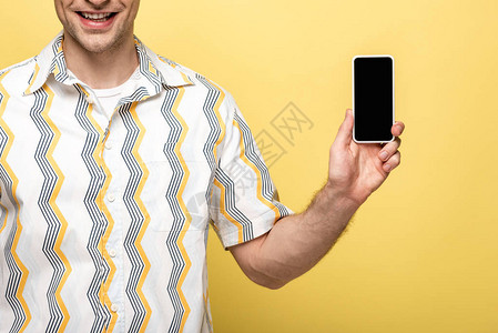 在黄色背景上带空白屏幕的手持智能手机的微背景图片