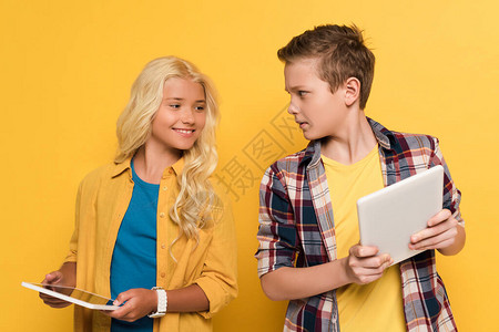 笑的孩子看着她朋友的黄色背景图片