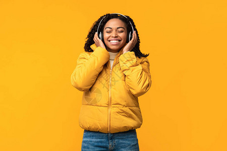 欢乐的黑人妇女聆听音乐无线耳机图片