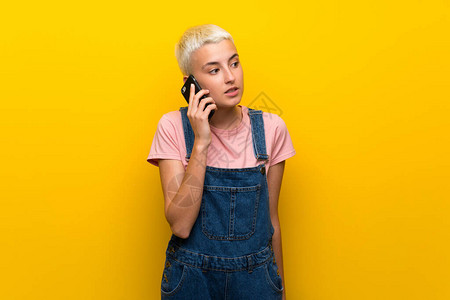 穿黄色背面的青少年女孩与手机保持通话单位图片
