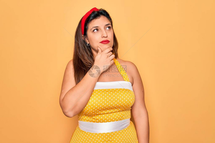 年轻的西班牙裔别针穿着时尚感的50年代风格在黄色背景上的女人图片