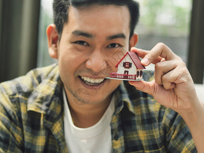 亚洲男子手里拿着房子模型计图片