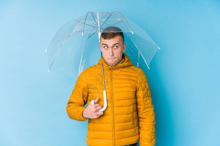 年轻caucasian男子拿着伞困惑图片