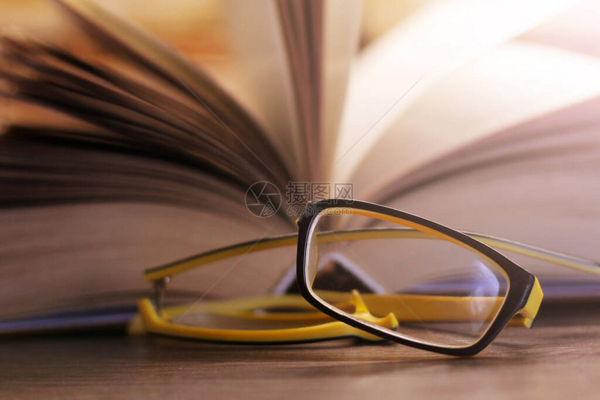 破碎的黄色眼镜和一本书如此接近图片