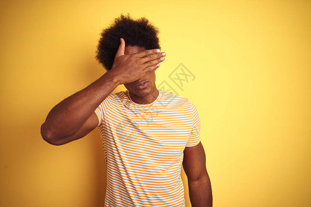 身穿条纹T恤的美国长发黑头发男子站在孤立的黄色背景上图片