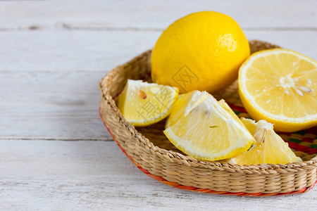 白色木质背景柳条碗中的柠檬角背景图片
