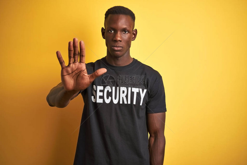 身穿安全制服的非洲裔美国安保人员在孤立的黄色背景下停止用手脸上带着消极和严肃的图片